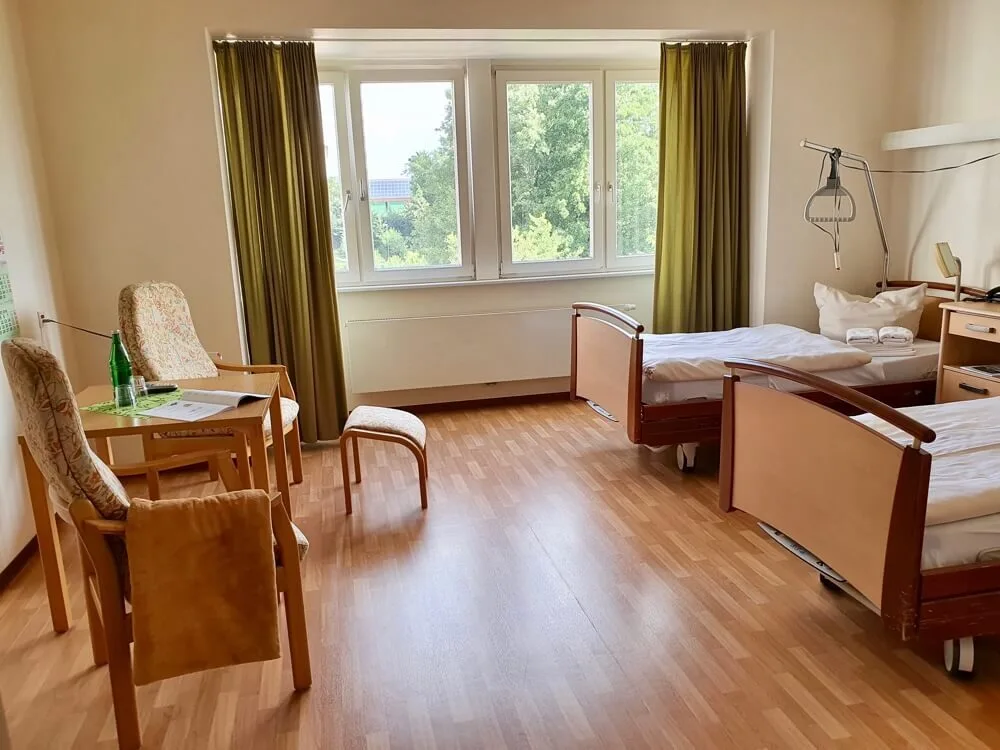Doppelzimmer auf der Geriatrischen Station mit Pflegebetten, Stühlen und Tisch