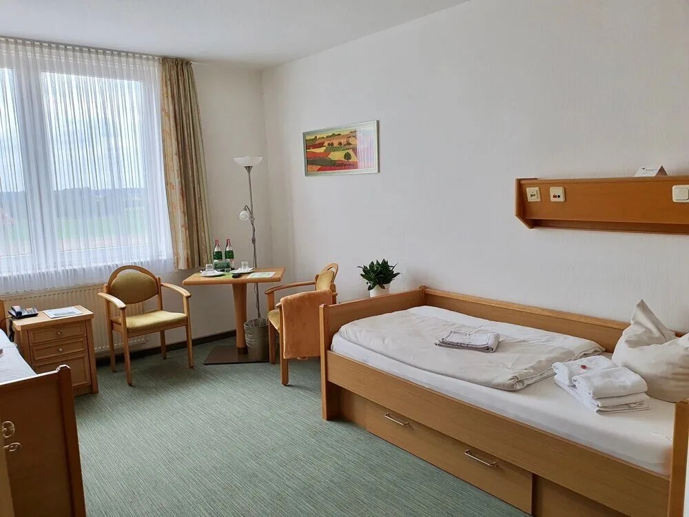 Doppelzimmer für orthopädische Patienten mit Pflegebetten, Stühlen und Tisch